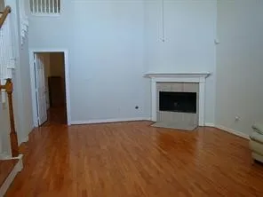a view of an empty room with wooden floor and a fireplace
