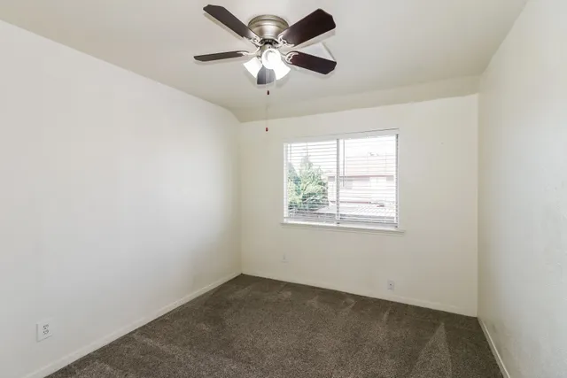 an empty room with a window and a fan