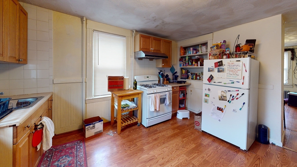 a view of a kitchen with fridge and wooden floor