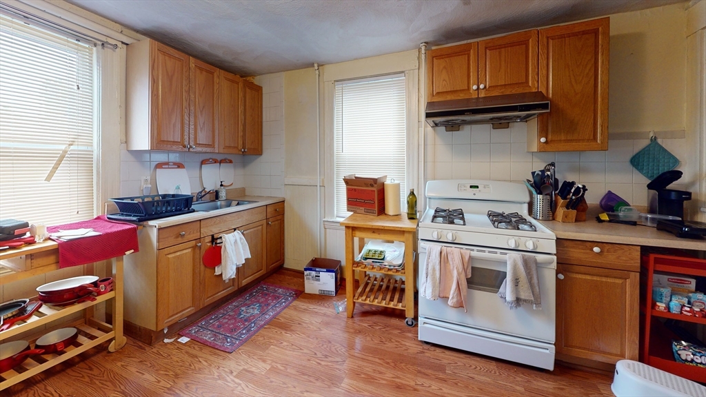 9 R Winship Street, Unit A Boston, MA 02135 - Photo 2 of 10 a kitchen with granite countertop a stove top oven a sink dishwasher and cabinets with wooden floor