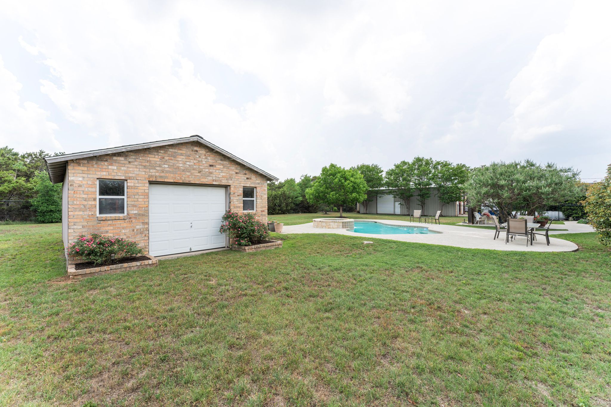 221 Breakaway Road Cedar Park, TX 78613 - Photo 17 of 39 View of green lawn with an outdoor pool, a patio, an outbuilding, and a garage