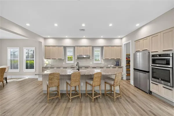 a kitchen with stainless steel appliances a dining table chairs stove refrigerator and wooden floor