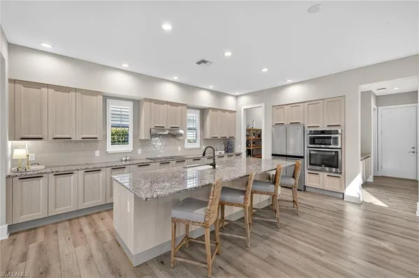 a kitchen with stainless steel appliances granite countertop a stove top oven a sink dishwasher and a refrigerator with wooden floor