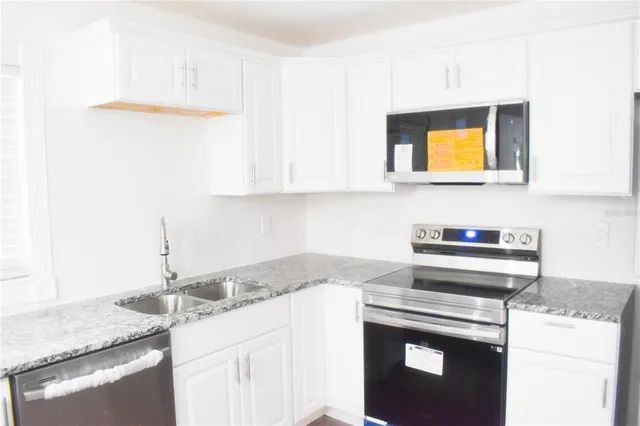 a kitchen with granite countertop cabinets stove top oven and sink