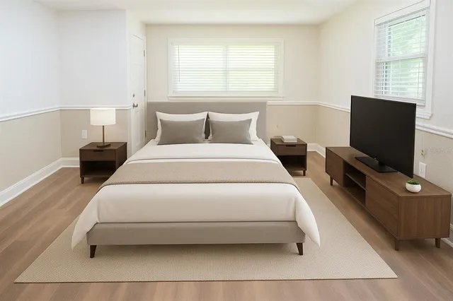 a bedroom with a bed a tv and wooden floor