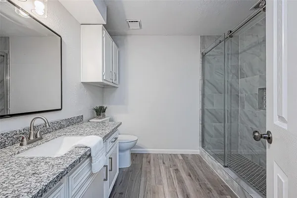 a bathroom with a granite countertop sink a mirror and shower