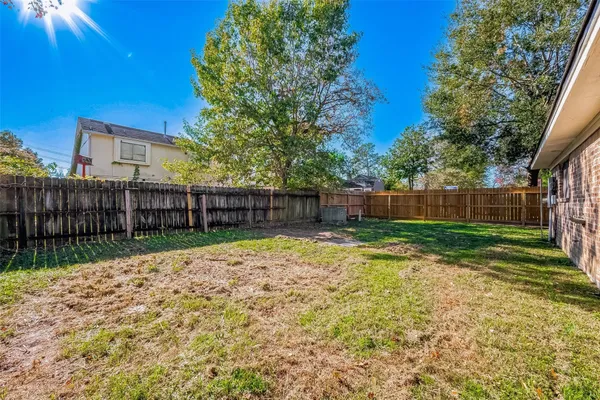 a view of a backyard with wooden fence and large trees
