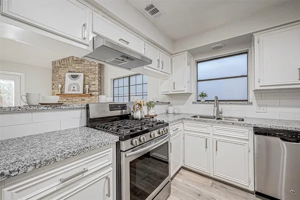 a kitchen with stainless steel appliances granite countertop a stove sink and cabinets