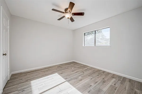 a view of empty room with wooden floor and ceiling fan