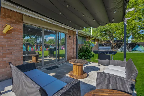 a view of a patio with table and chairs potted plants and large tree