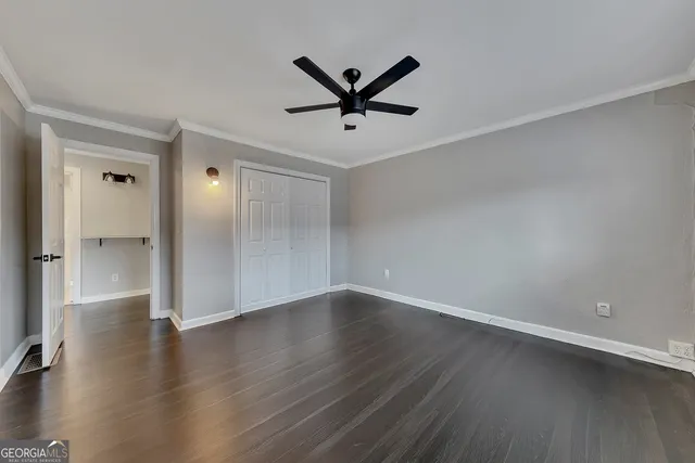 an empty room with wooden floor and a ceiling fan