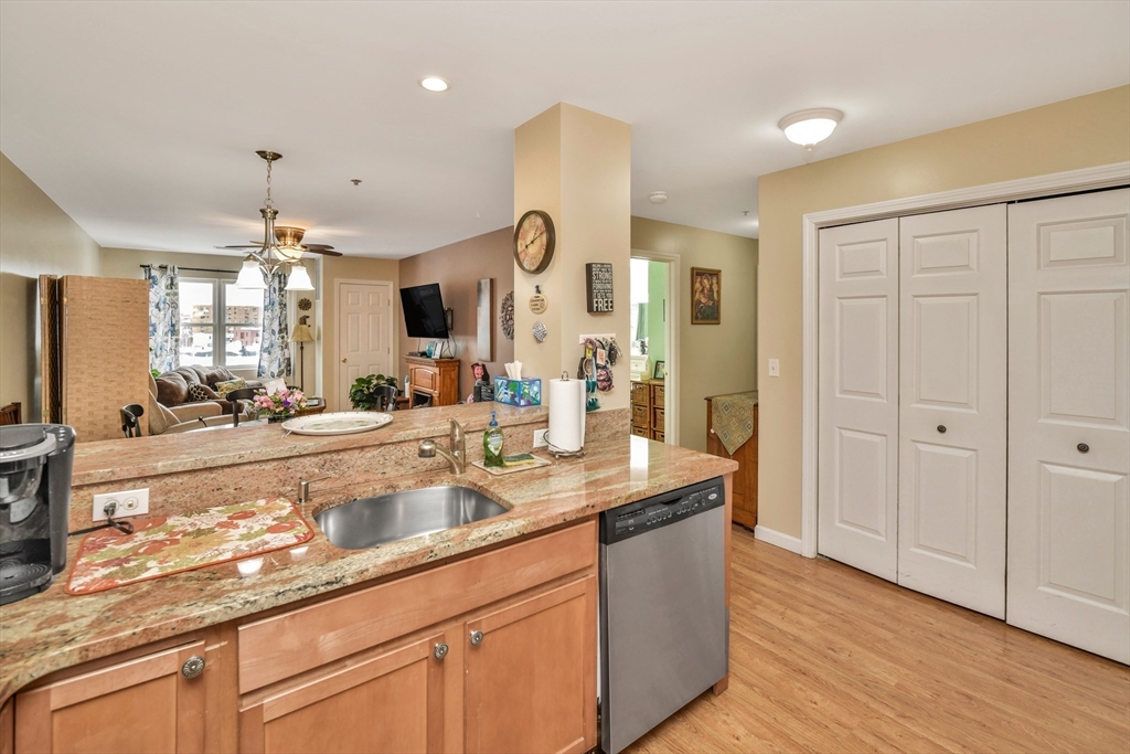 75 Walnut Street, Unit 315 Peabody, MA 01960 - Photo 2 of 14 a large kitchen with granite countertop a sink dishwasher a dining table and chairs with wooden floor