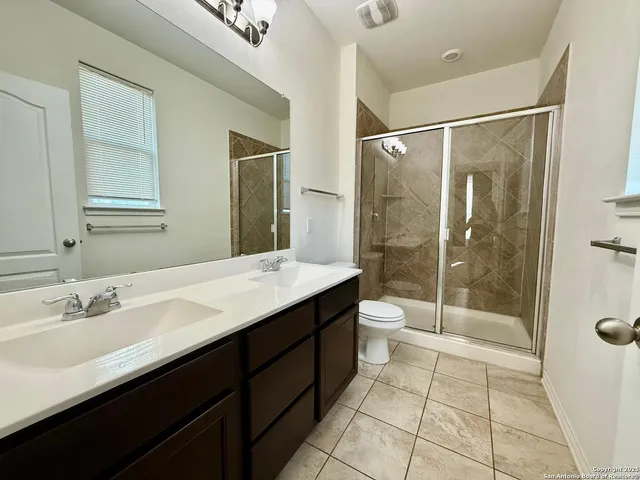 a bathroom with a granite countertop sink toilet a mirror and shower