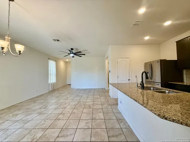 a large kitchen with granite countertop a sink a counter top space and cabinets