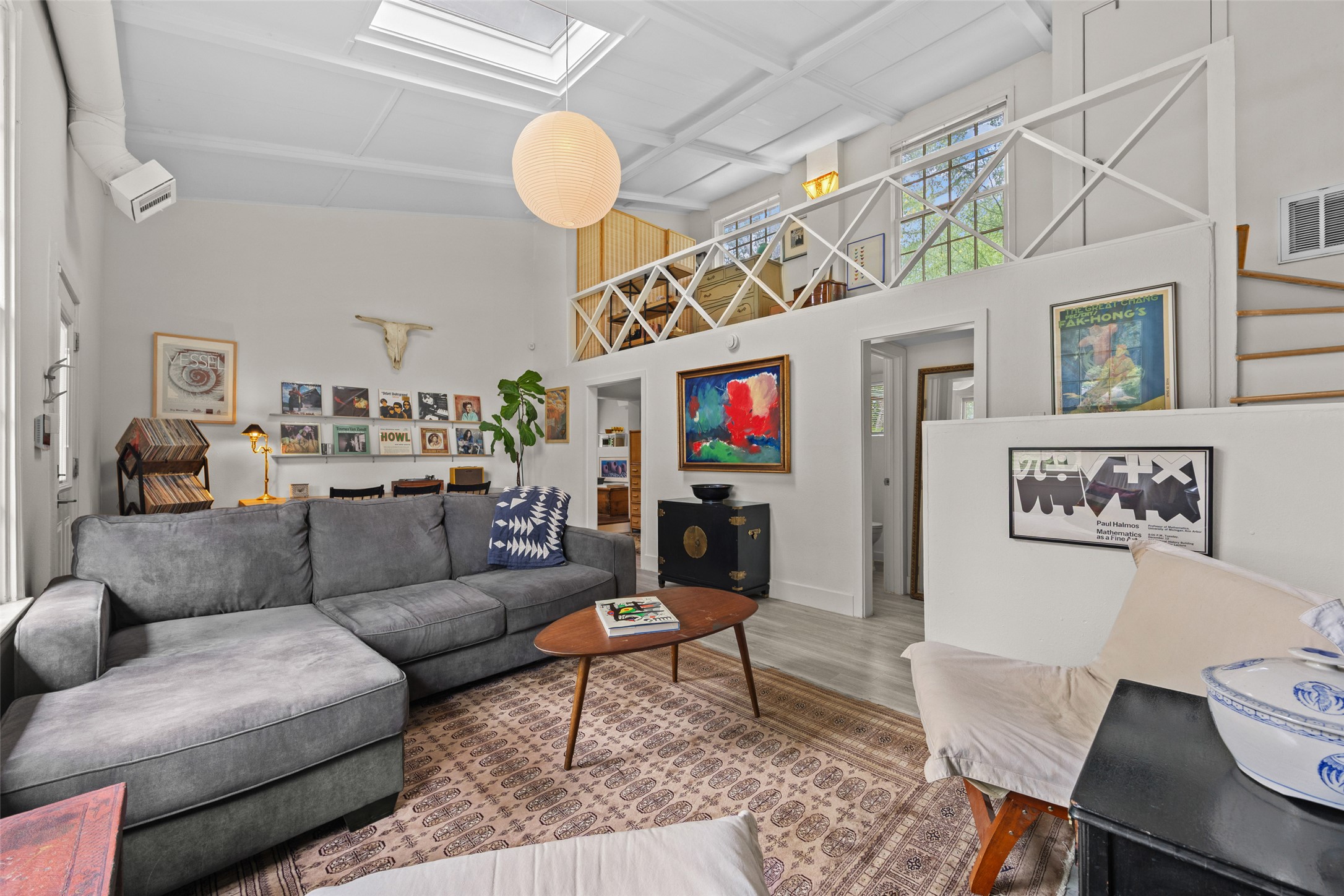 3302 Cherrywood Road Austin, TX 78722 - Photo 4 of 26 A spacious living room features soaring ceilings, a sun-filled skylight, and an inviting mezzanine loft.