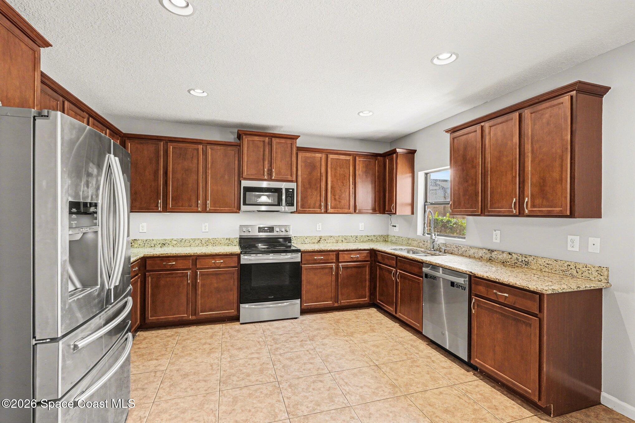 1363 Hailey Street Melbourne, FL 32904 - Photo 16 of 41 a large kitchen with stainless steel appliances granite countertop a stove top oven a sink and dishwasher