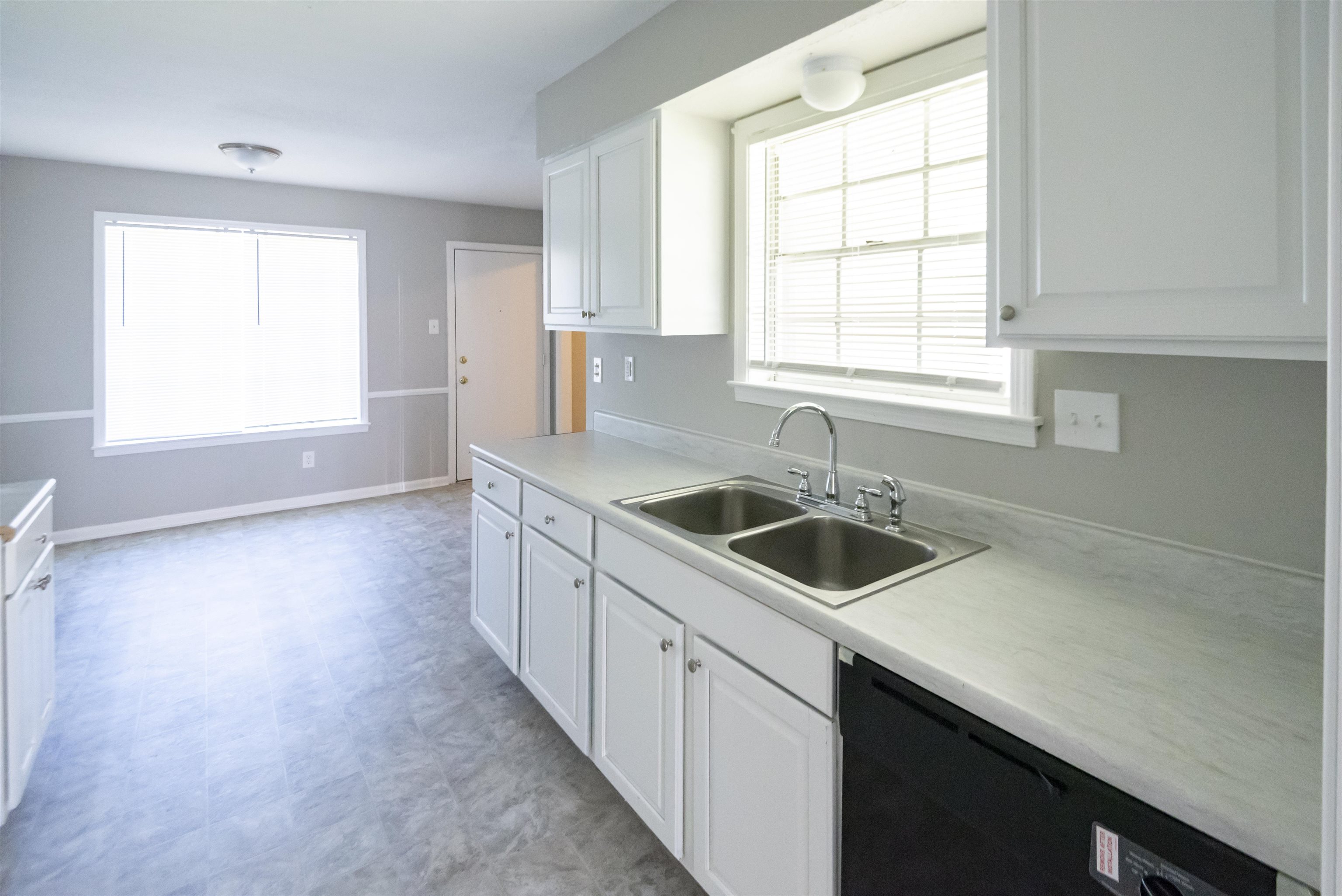4399 Pepper Tree Road Memphis, TN 38109 - Photo 7 of 14 Kitchen with white cabinets, light countertops, light floors, and black dishwasher