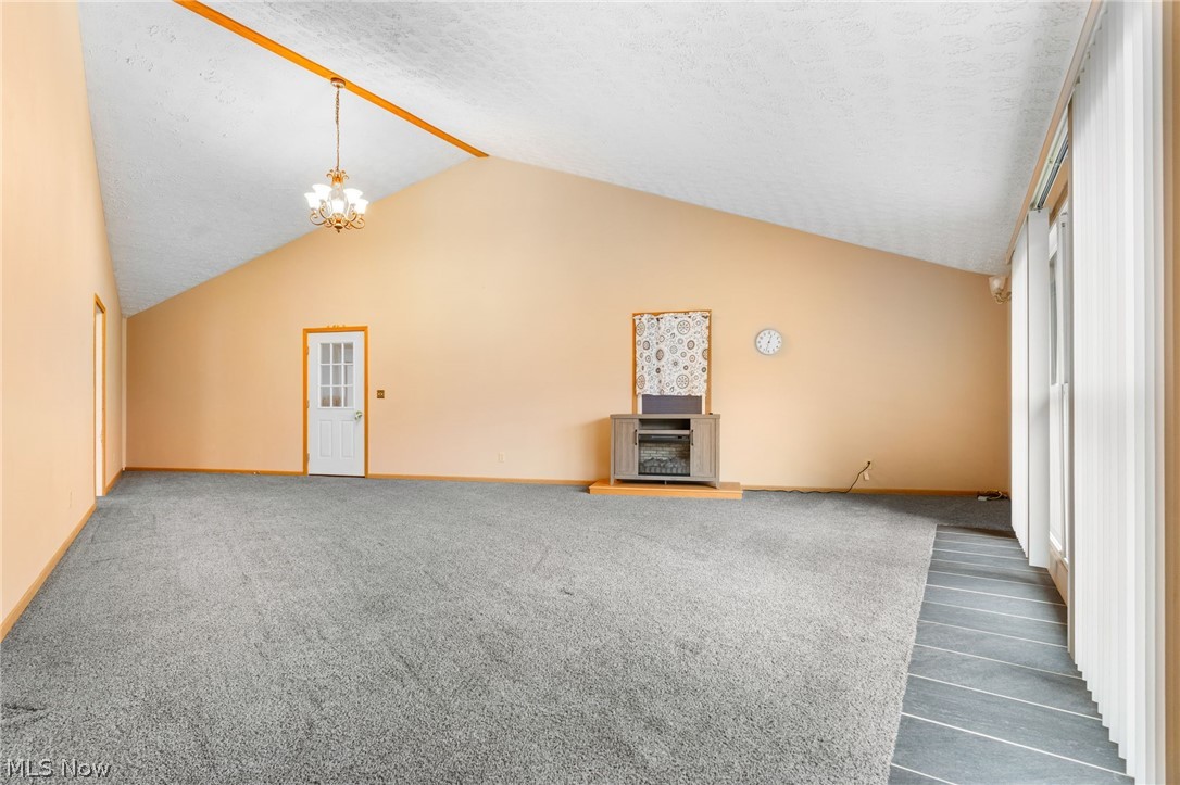 1640 Old Delaware Road Mount Vernon, OH 43050 - Photo 25 of 49 Unfurnished living room featuring dark carpet, a chandelier, a textured ceiling, and a fireplace