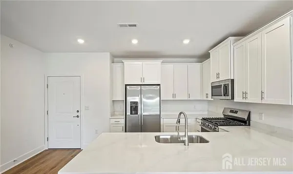 a kitchen with granite countertop white cabinets and stainless steel appliances