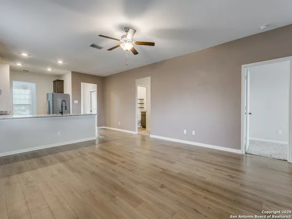 a view of an empty room with wooden floor and a window