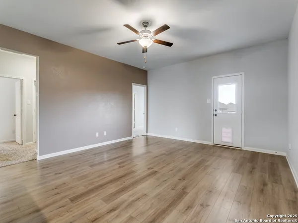 an empty room with wooden floor and ceiling fan