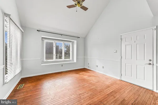 a view of empty room with wooden floor and fan