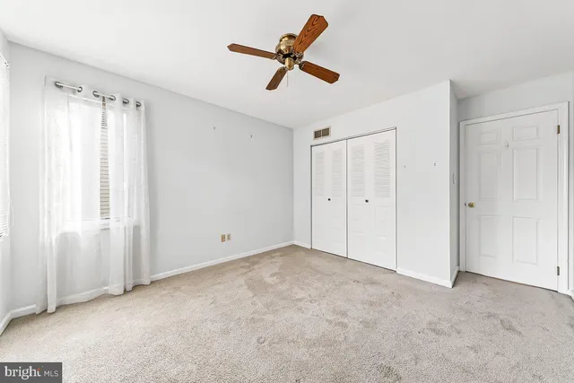 an empty room with ceiling fan and window