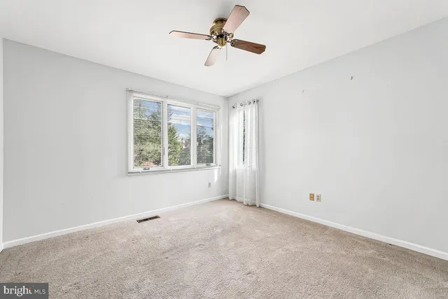 an empty room with a window and a ceiling fan