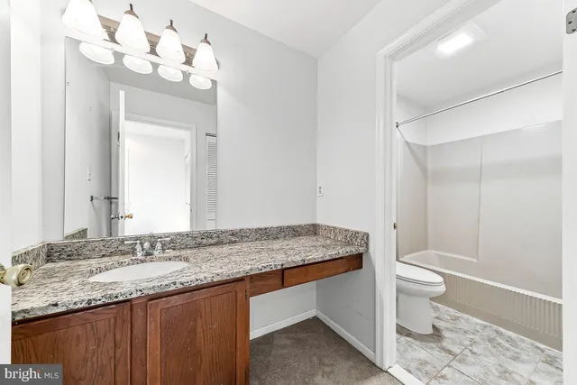 a bathroom with a granite countertop sink a toilet and a mirror