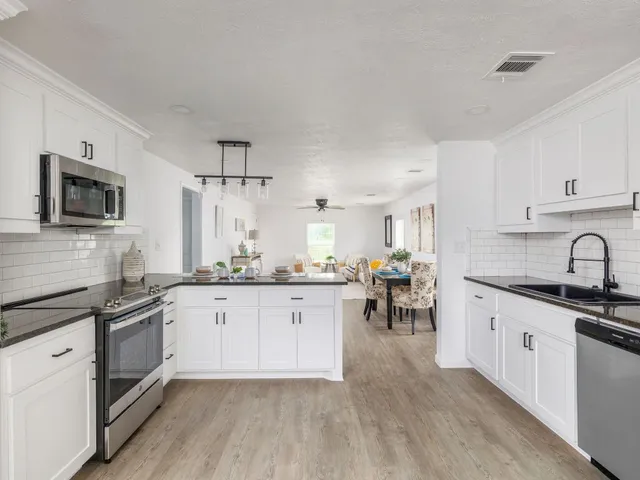 a kitchen with granite countertop white cabinets white stainless steel appliances and a sink