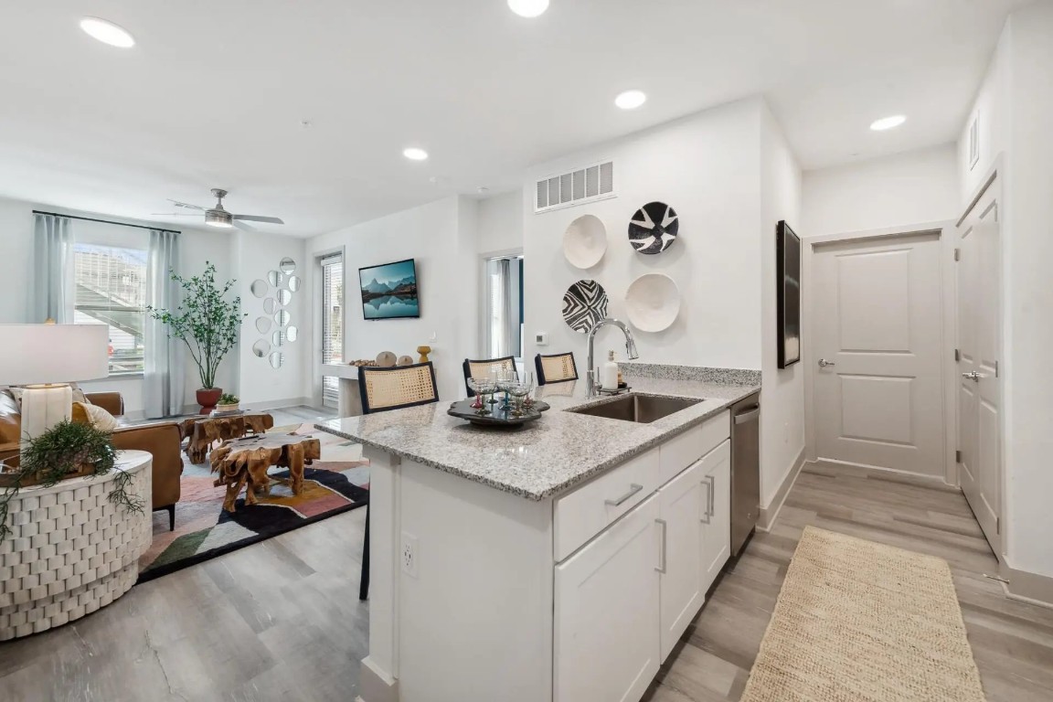 945 Blakey Lane, Unit 10304 Bastrop, TX 78602 - Photo 7 of 29 a kitchen with stainless steel appliances granite countertop a sink dishwasher and a flat tv screen next to a large window