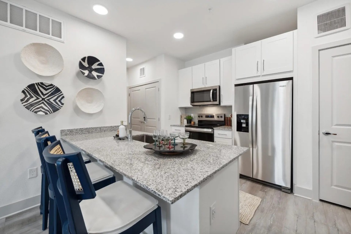 945 Blakey Lane, Unit 10304 Bastrop, TX 78602 - Photo 8 of 29 a kitchen with granite countertop kitchen island stainless steel appliances a sink counter space and center island