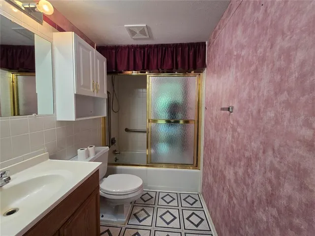 an empty room with a chandelier fan and windows