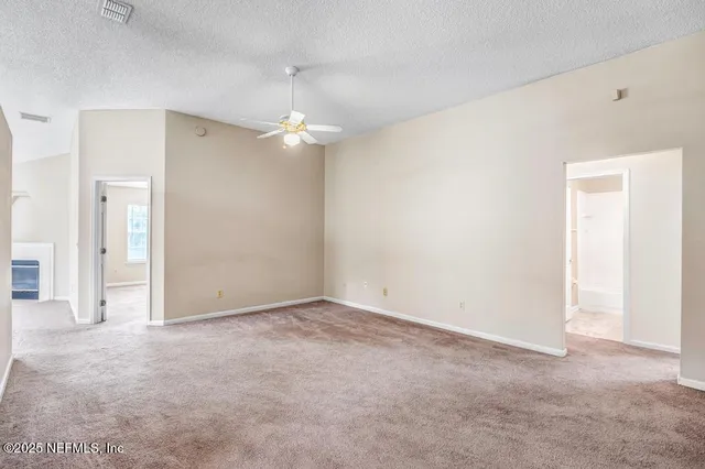an empty room with a ceiling fan and a bathroom