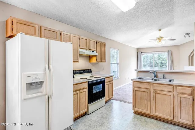 a kitchen with stainless steel appliances granite countertop a refrigerator a sink a stove with white cabinets