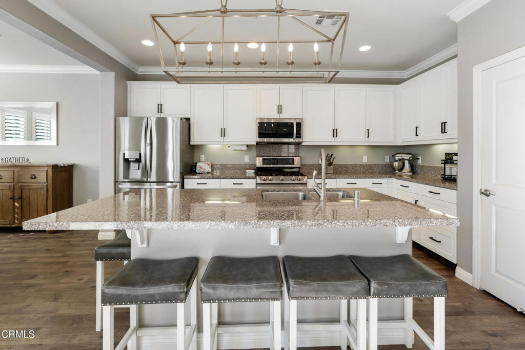 668 Whalen Way Oxnard, CA 93036 - Photo 8 of 57 a kitchen with stainless steel appliances granite countertop a stove top oven a refrigerator a sink and a dining table with white cabinets