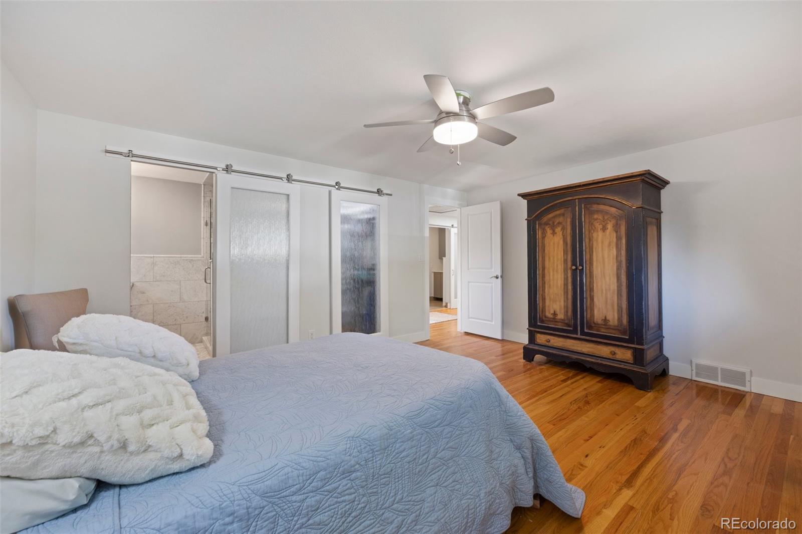 703 South Oneida Way Denver, CO 80224 - Photo 12 of 24 a bedroom with a large bed and a chandelier