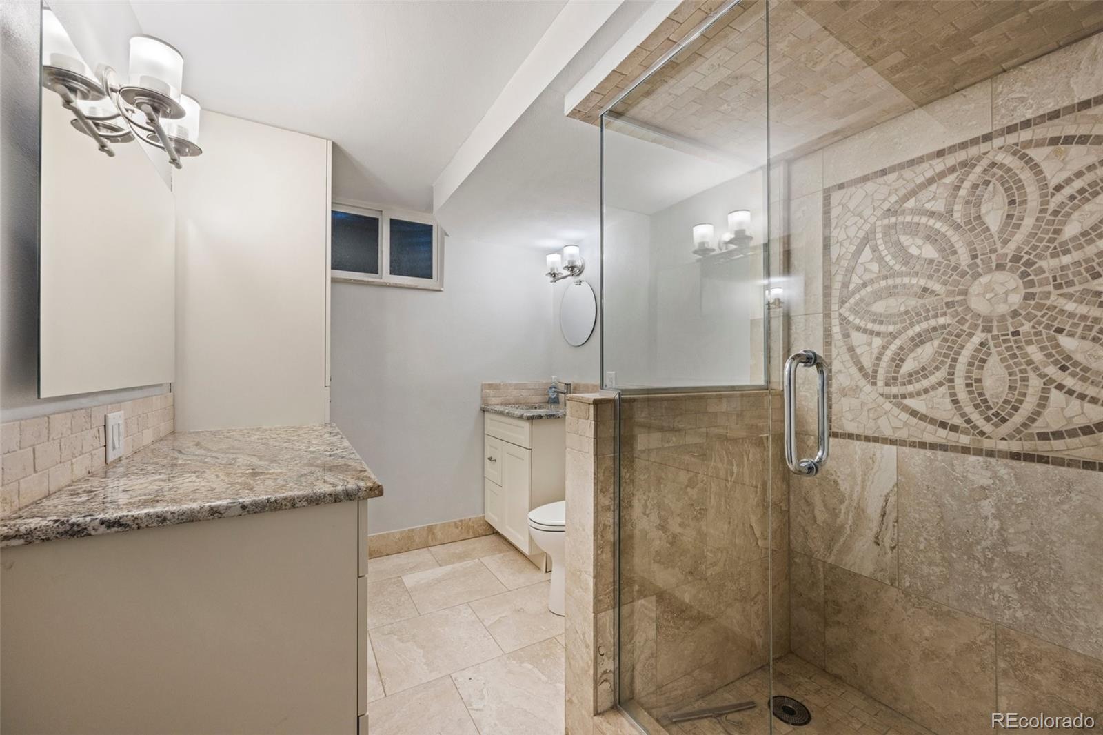 703 South Oneida Way Denver, CO 80224 - Photo 21 of 24 a bathroom with a granite countertop sink a mirror and shower