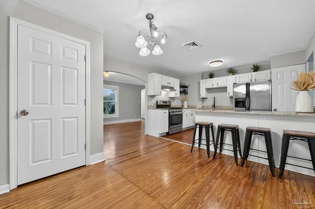 a dining room with wooden floor a chandelier a wooden table and chairs