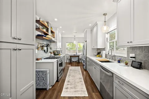 a kitchen with stainless steel appliances granite countertop a sink a stove a refrigerator and cabinets