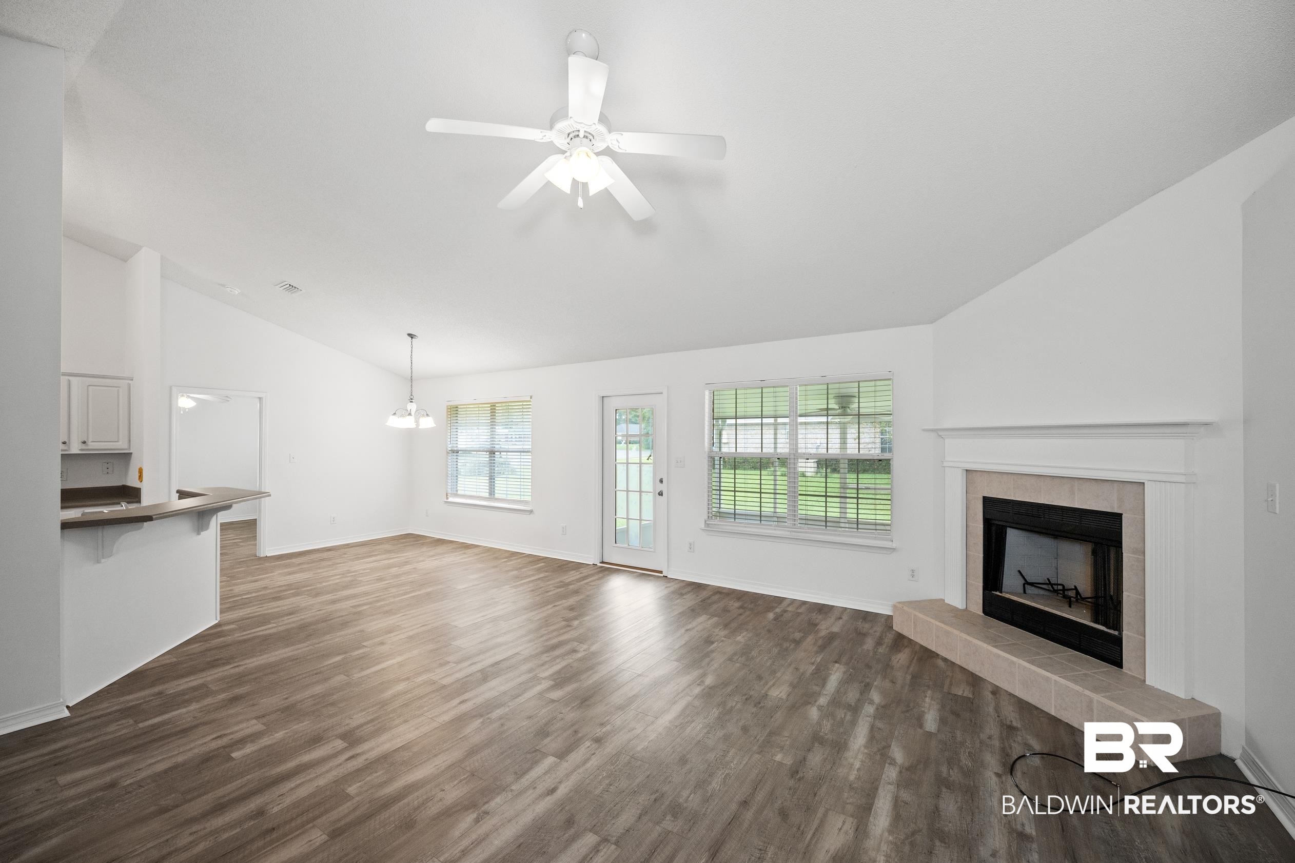 306 Monteith Oaks Drive Foley, AL 36535 - Photo 3 of 38 Unfurnished living room with lofted ceiling, dark wood finished floors, a tile fireplace, a ceiling fan, and a chandelier