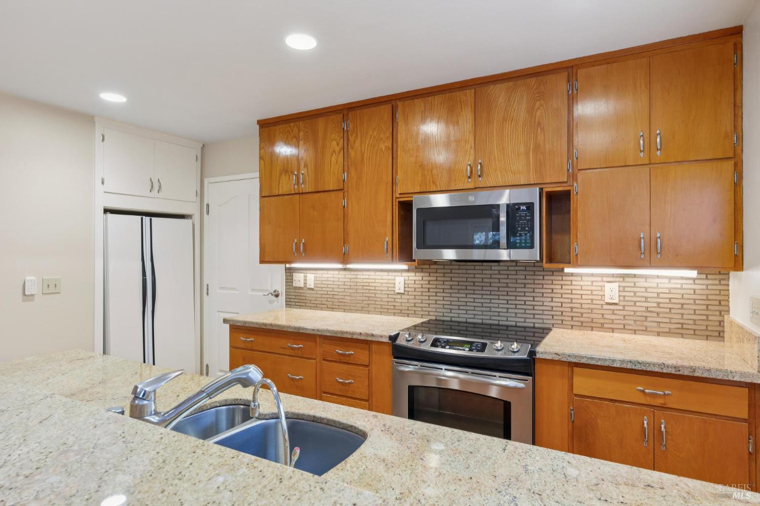 561 Olive Avenue Novato, CA 94945 - Photo 17 of 50 a kitchen with stainless steel appliances granite countertop a sink stove and microwave