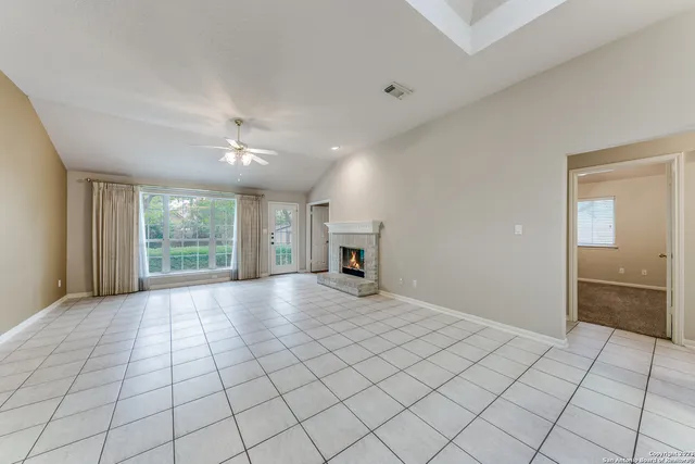 a view of a livingroom with a fireplace a chandelier fan and wooden floor