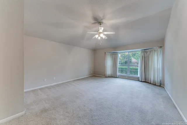 an empty room with windows and chandelier fan