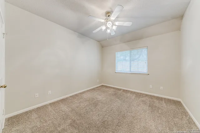 an empty room with a chandelier fan and windows