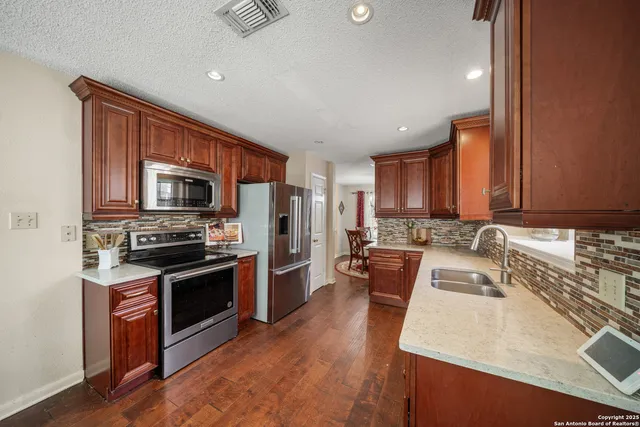 a kitchen with stainless steel appliances granite countertop a sink stove microwave and refrigerator