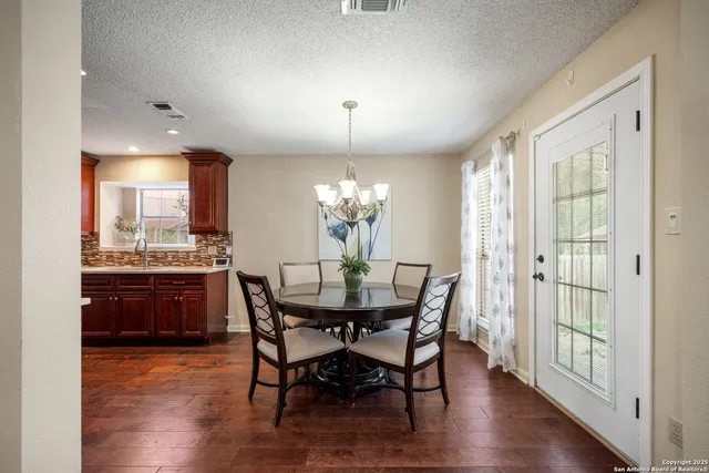 a dining room with furniture a chandelier and wooden floor