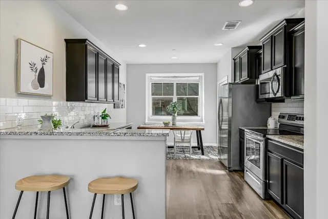 a kitchen with stainless steel appliances a sink a stove a refrigerator cabinets and a dining table