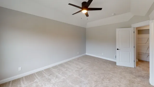 an empty room with a ceiling fan and carpet