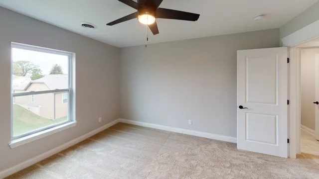 an empty room with a window and a ceiling fan